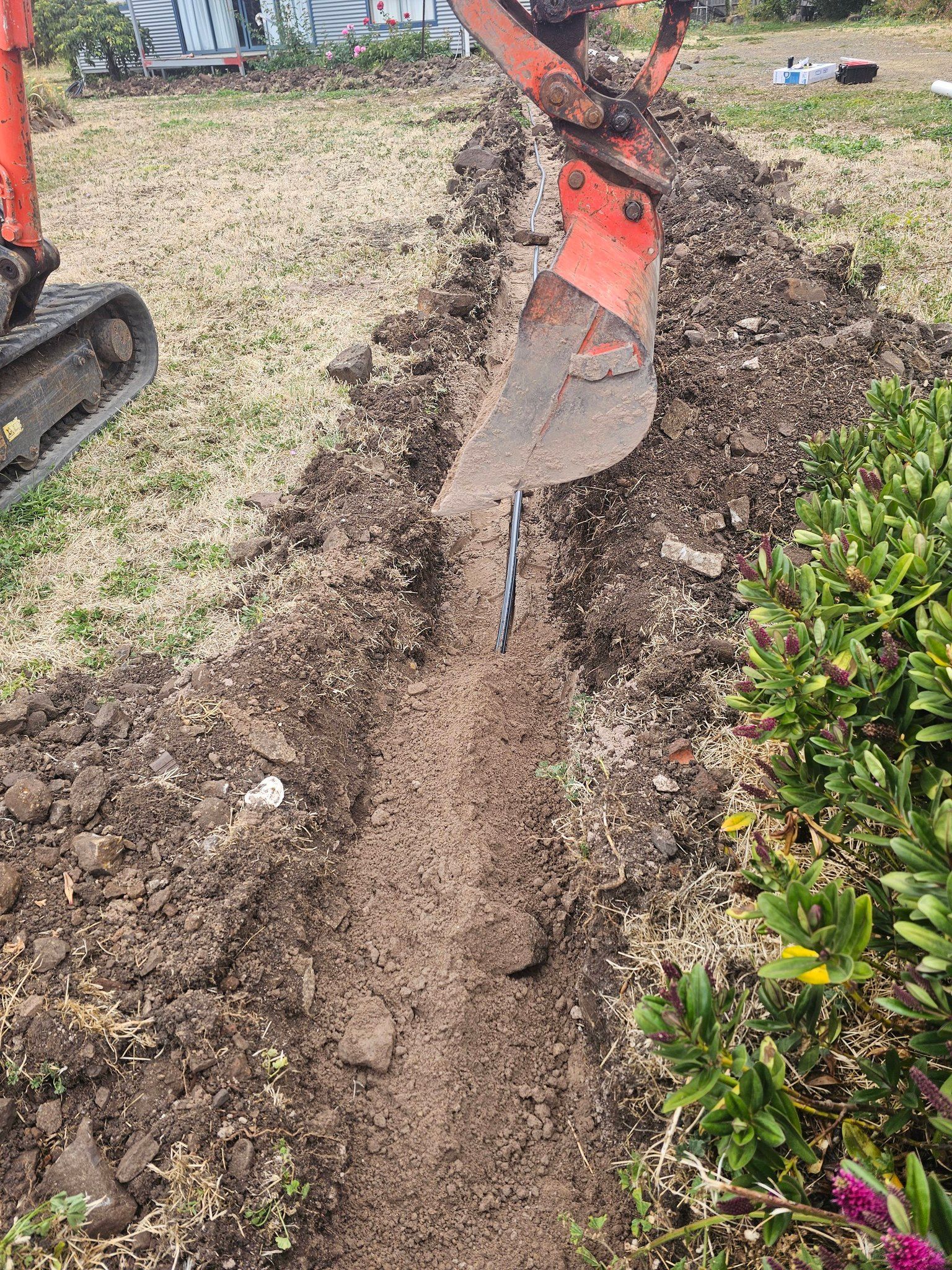 An Orange Excavator Arm Digs a Narrow Trench — Lenny's Plumbing & Contracting in Granton, TAS