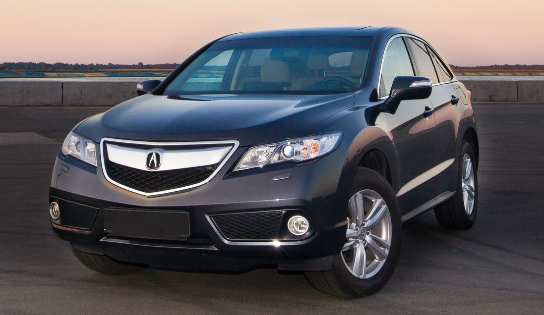 A white GMC Yukon SUV driving on a highway with chrome rims during the daytime.