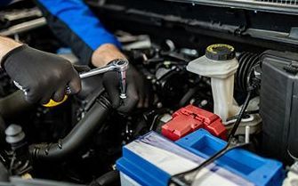 A man is working on the engine of a car with a wrench.