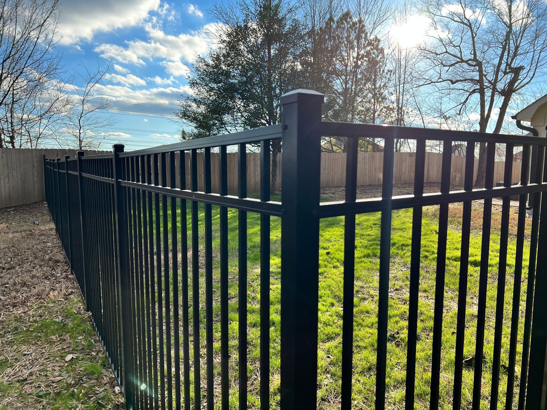 A black metal fence surrounds a lush green yard.