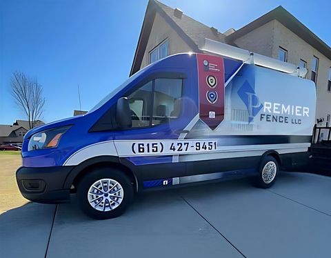 A blue and white van is parked in front of a house.