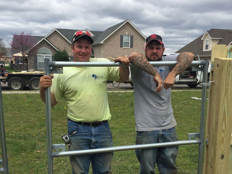 Two men standing next to each other in front of a house