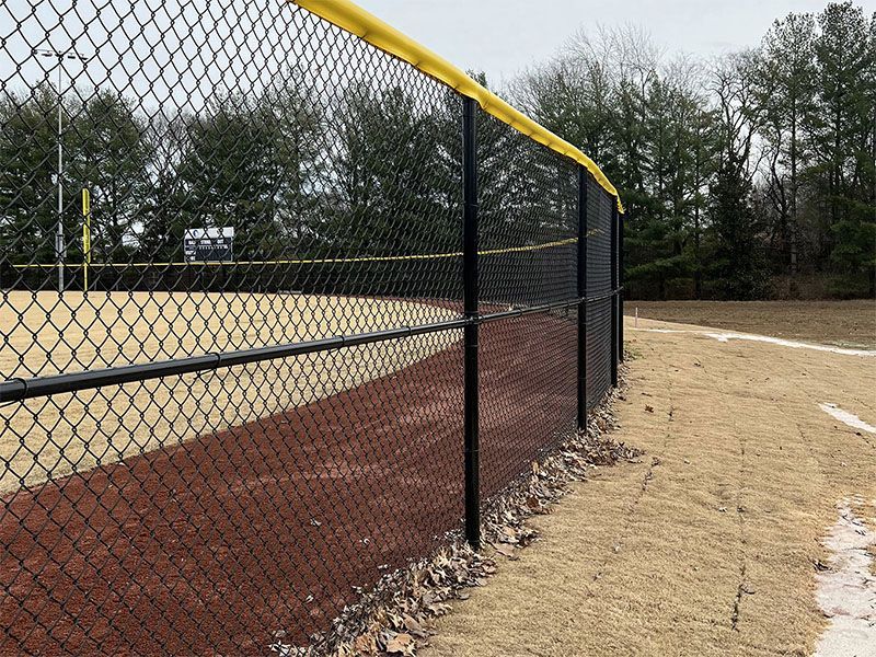 A chain link fence surrounds a baseball field.
