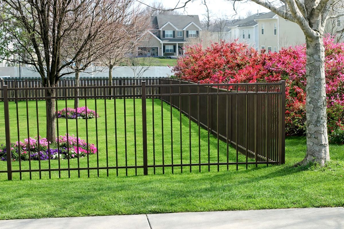 A black metal fence with a shadow on a white background.
