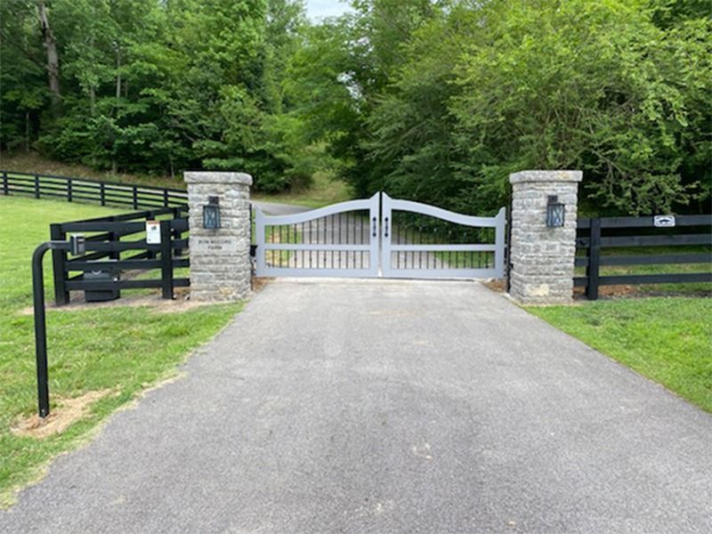 A driveway with a gate and a stone pillar