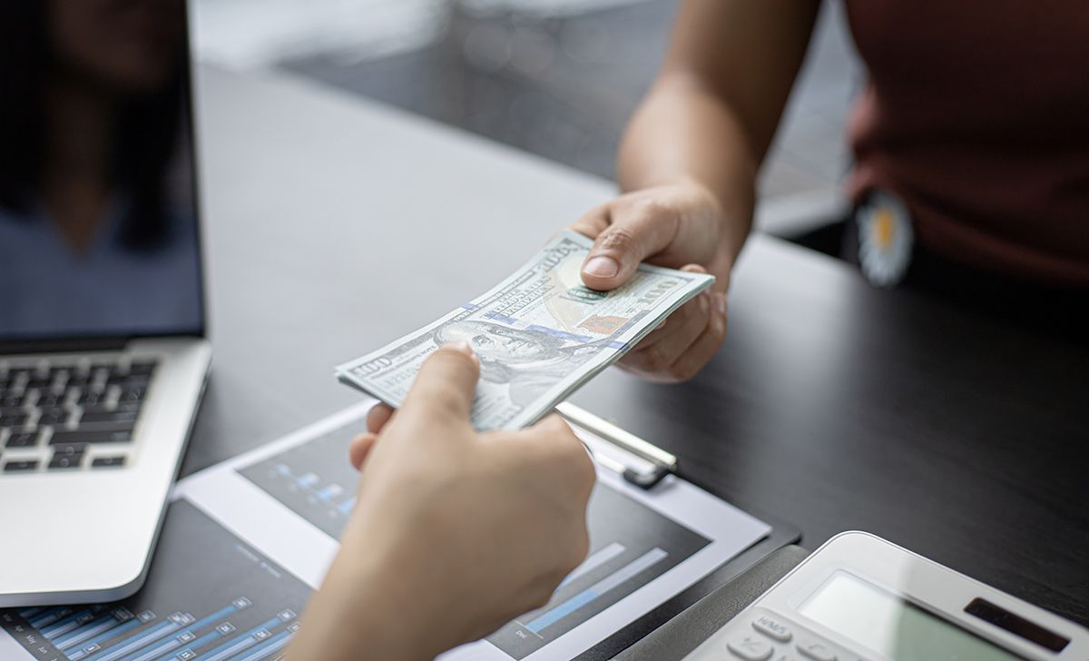 A person is handing another person a bunch of money.
