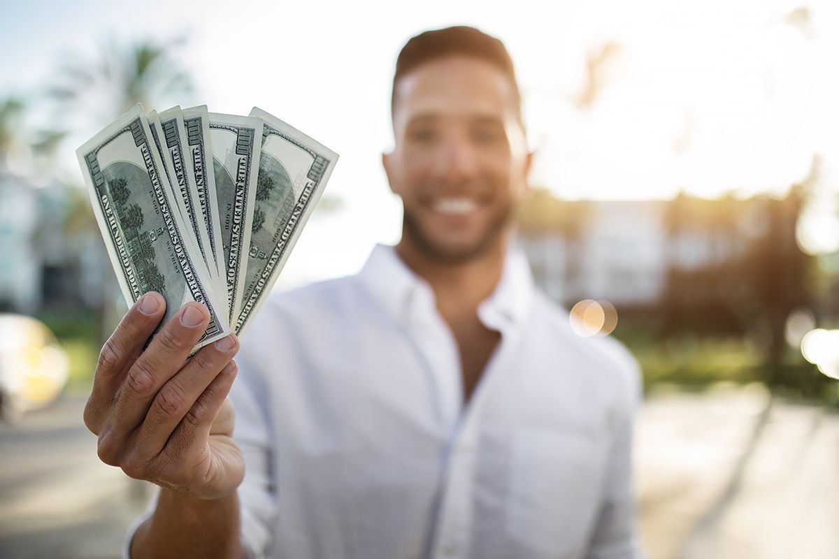 A man is holding a fan of money in his hand.