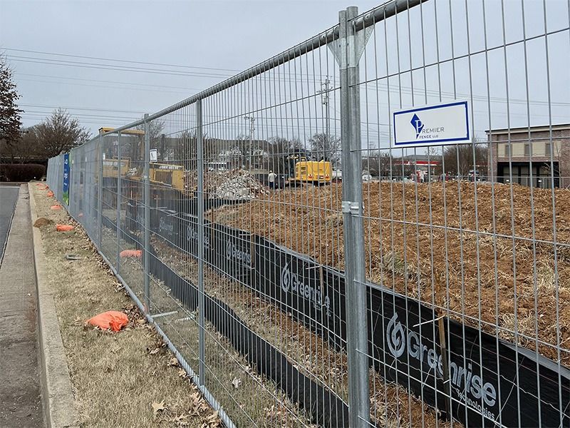 A fence with a sign on it is surrounding a construction site.