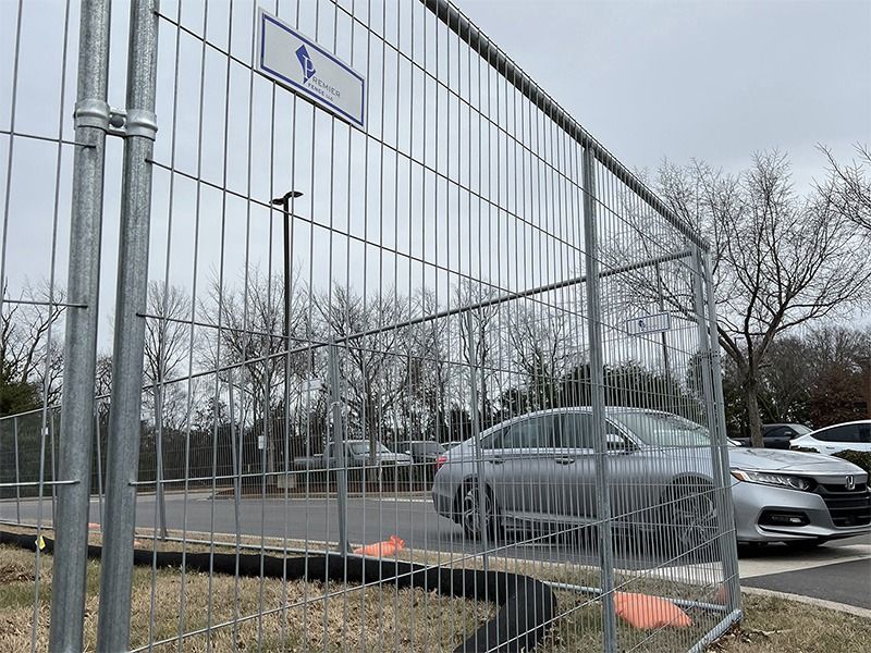 A car is parked behind a fence in a parking lot.
