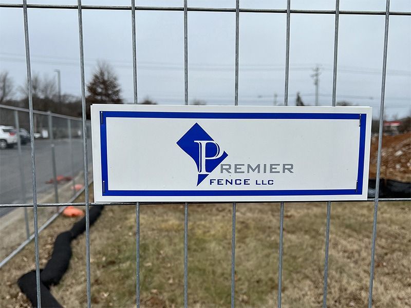 A sign on a fence that says premier fence llc