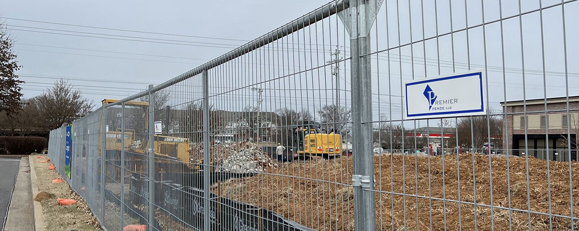 A fence with a sign on it is surrounding a construction site.