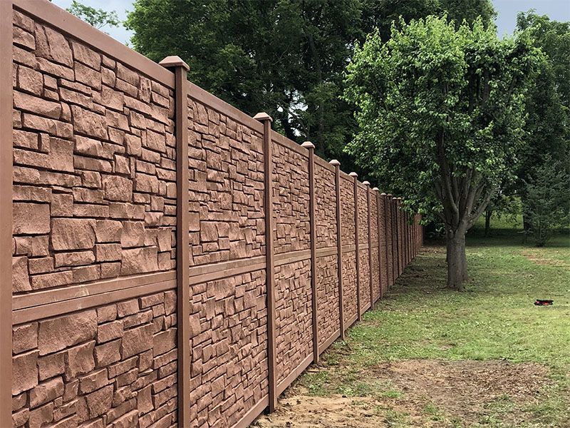 A stone fence surrounds a grassy field with trees in the background.
