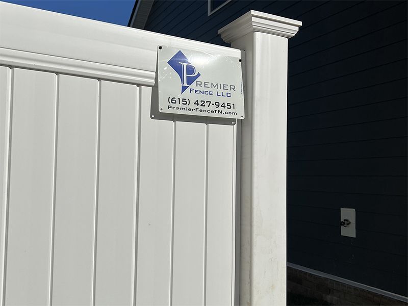 A white fence with a sign that says premier fence llc