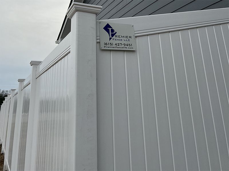 A white fence with a sign attached to it
