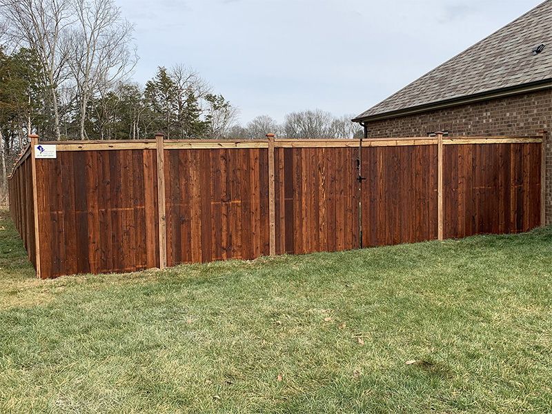 A wooden fence is in the backyard of a house.