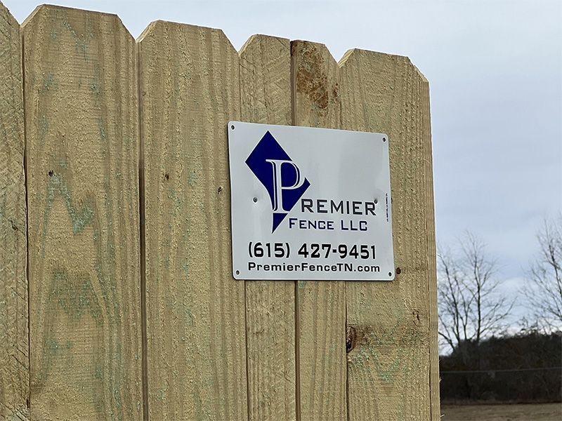 A wooden fence with a sign on it that says premier fence llc