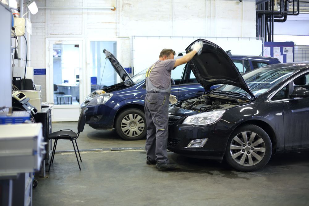 A Man is Inspecting a Car in a Garage With the Hood Open — PT AUTO In Cardiff, NSW