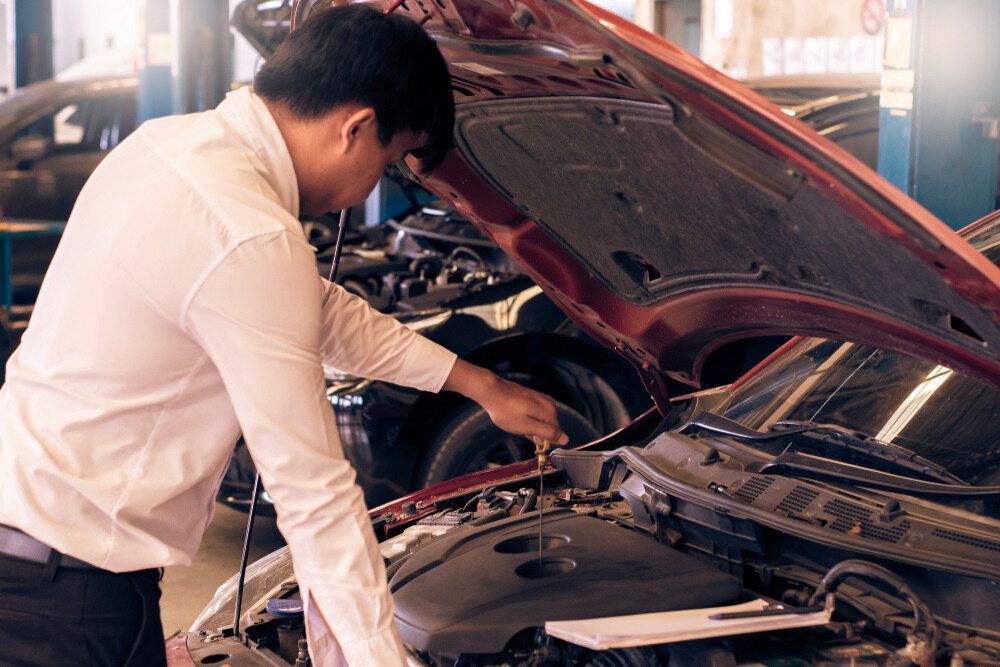 A Man is Looking Under the Hood of a Car in a Garage — PT AUTO In Cardiff, NSW