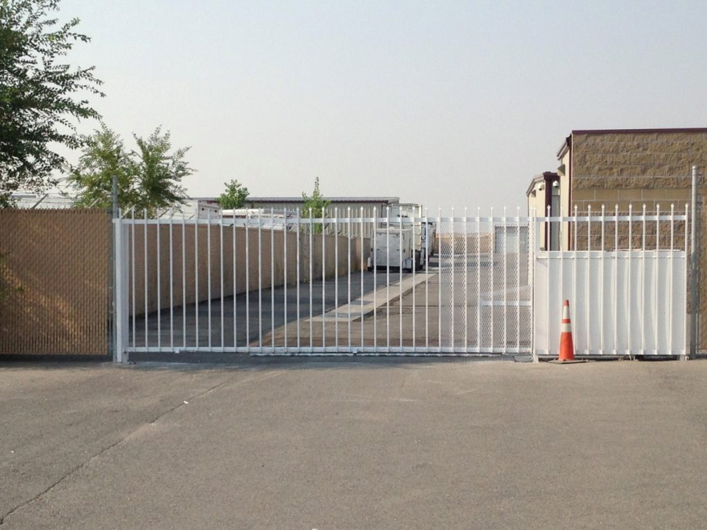 A white gate is open to a parking lot