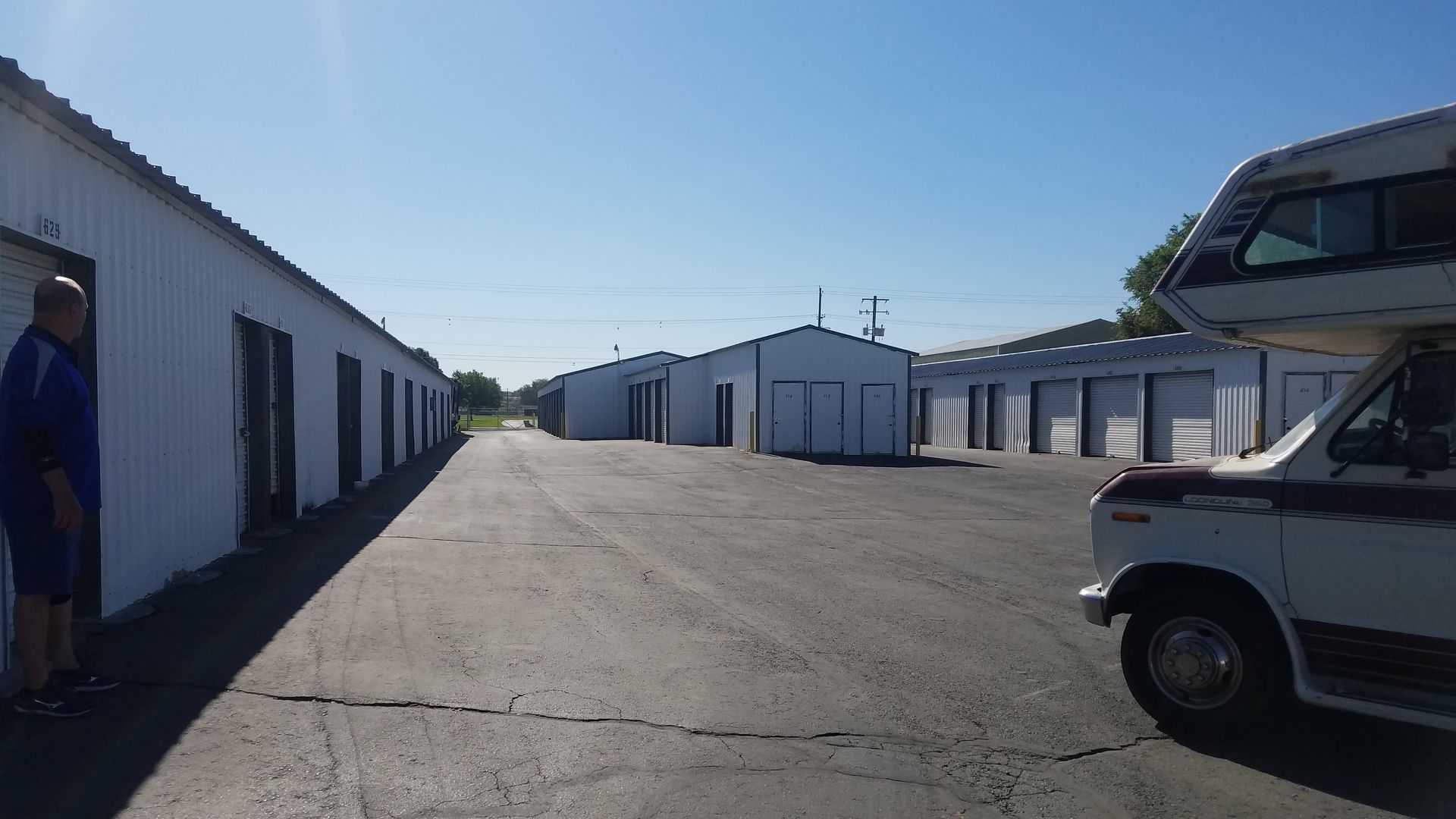 A white van is parked in front of a row of white buildings