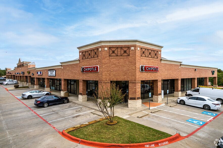A brick building with cars parked in front of it in a parking lot.