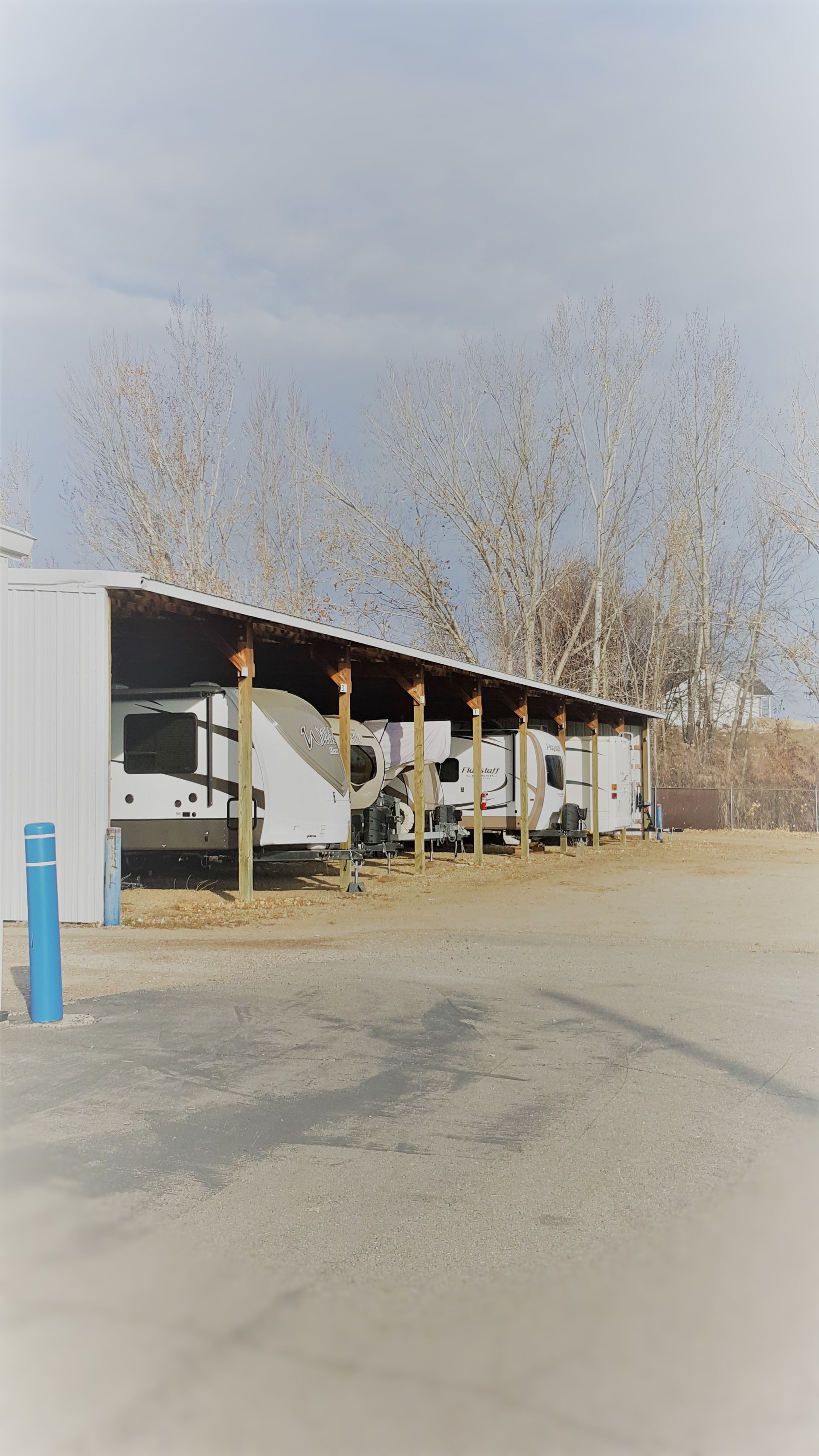 A row of rvs parked under a shed in a parking lot.