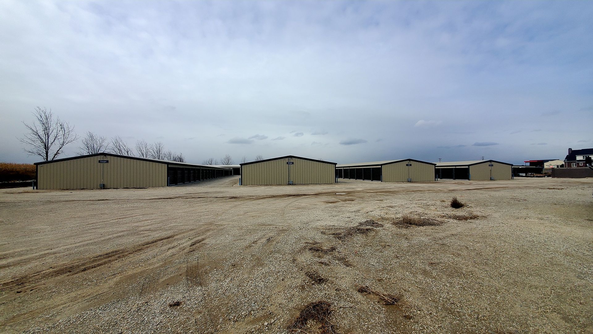 A row of sheds are lined up in a gravel lot.