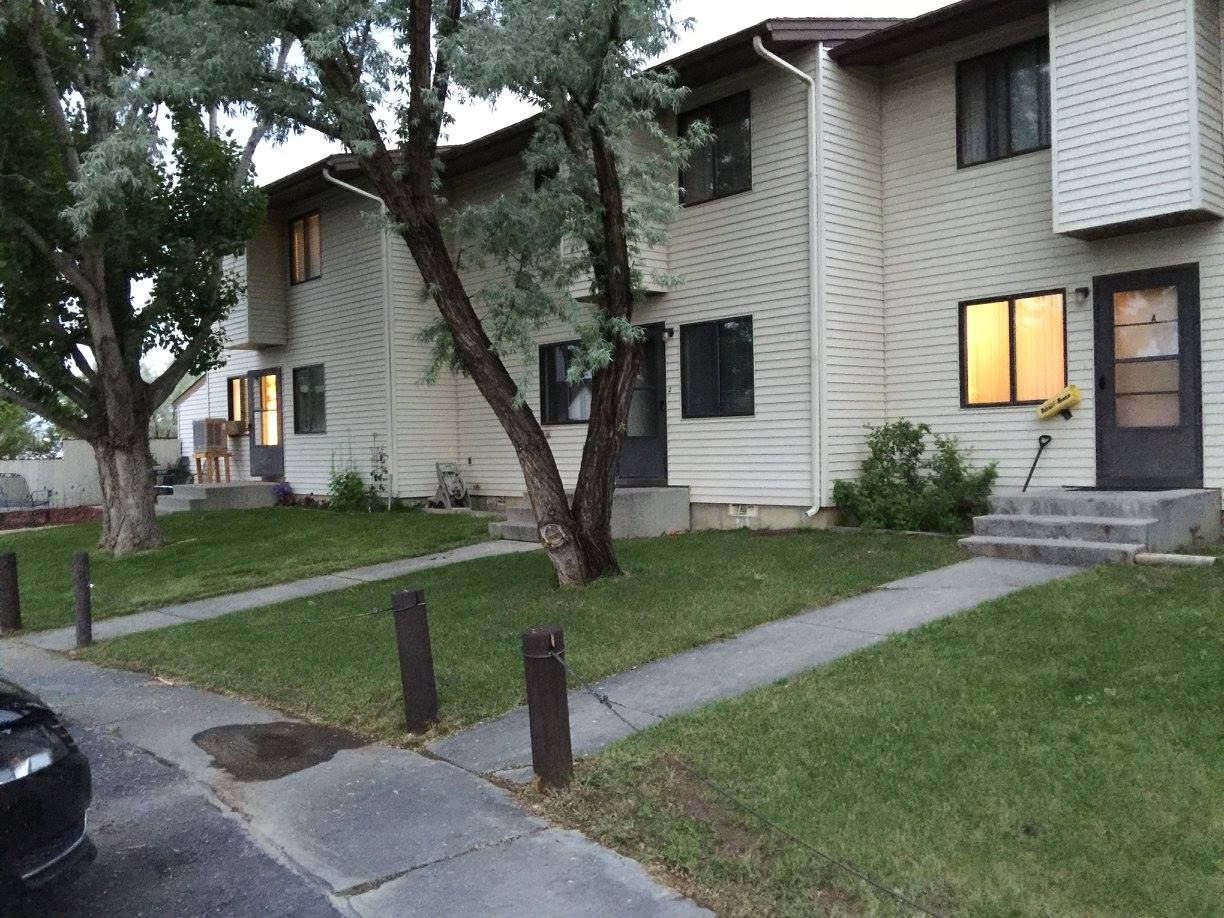 A white apartment building with a black car parked in front of it