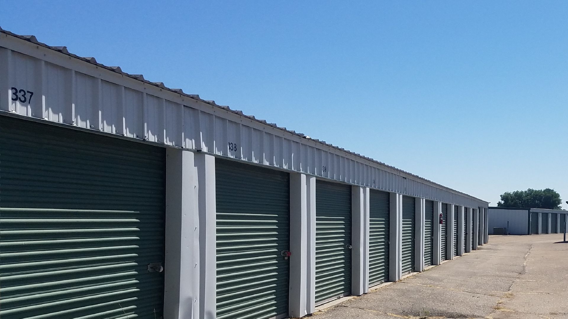 A row of storage units with green doors on a sunny day