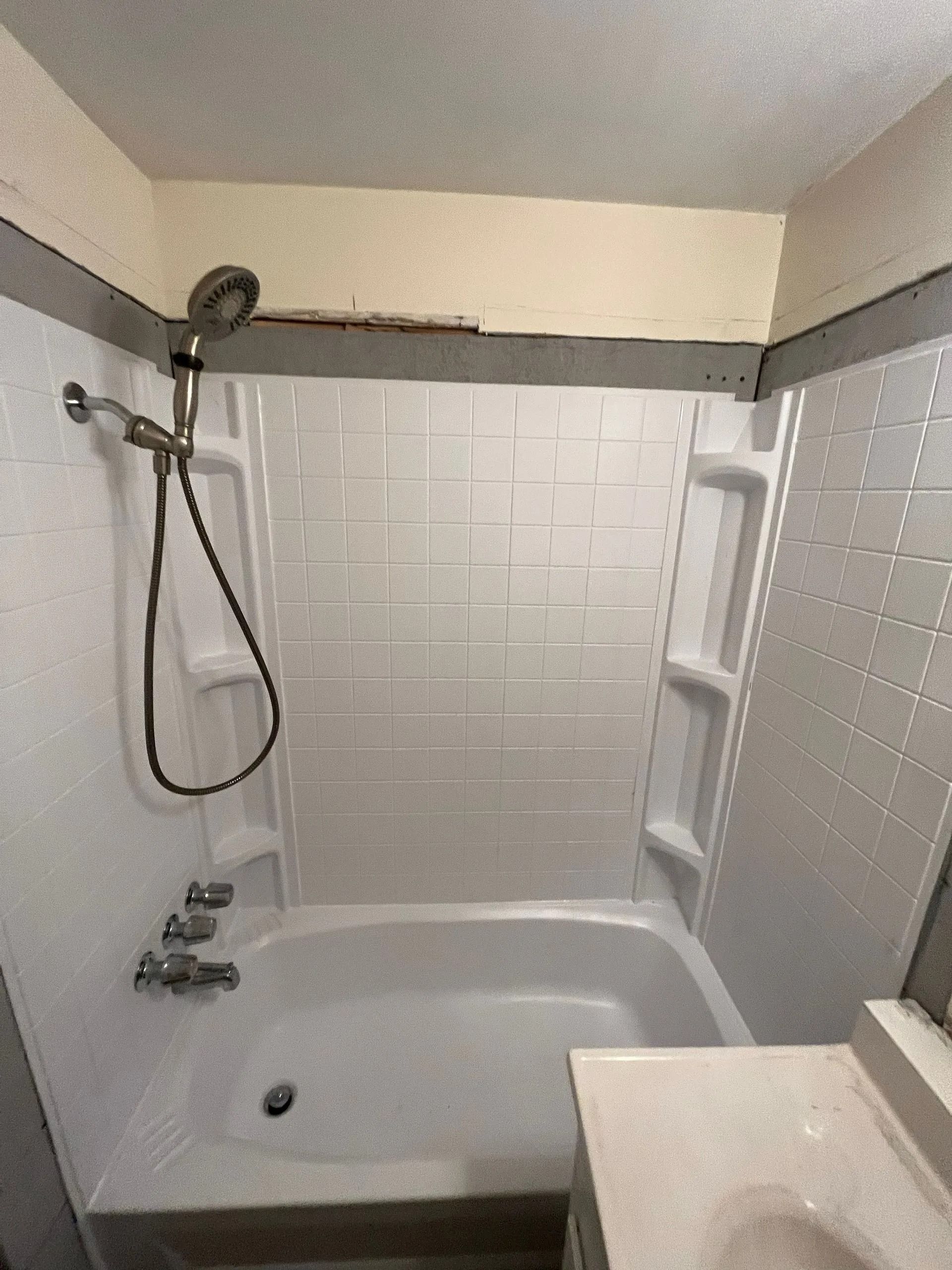 White bathtub and shower combo in a bathroom; silver shower head and faucet.