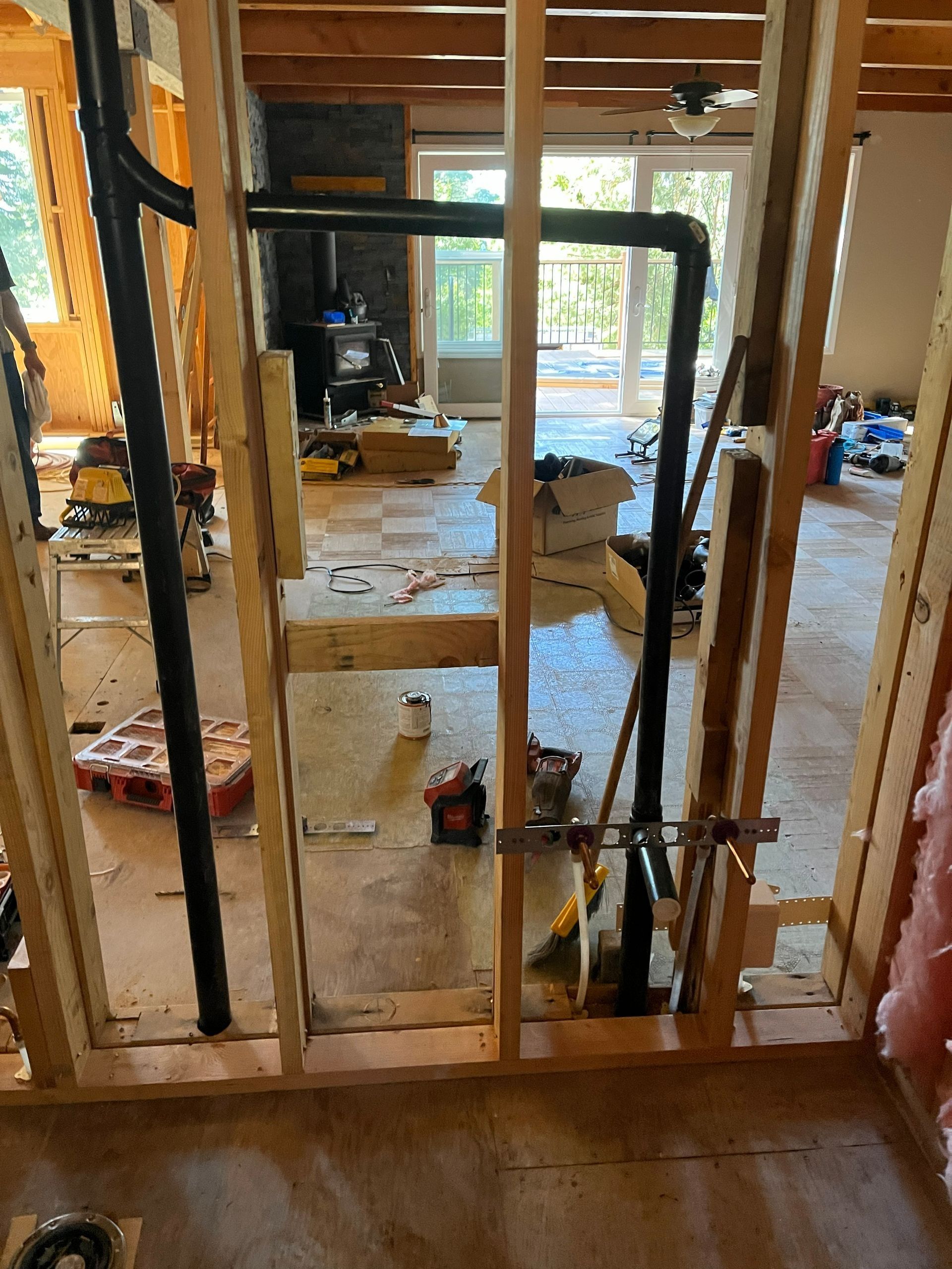 Plumbing pipes installed within the framing of a wall, interior view of a room under construction.