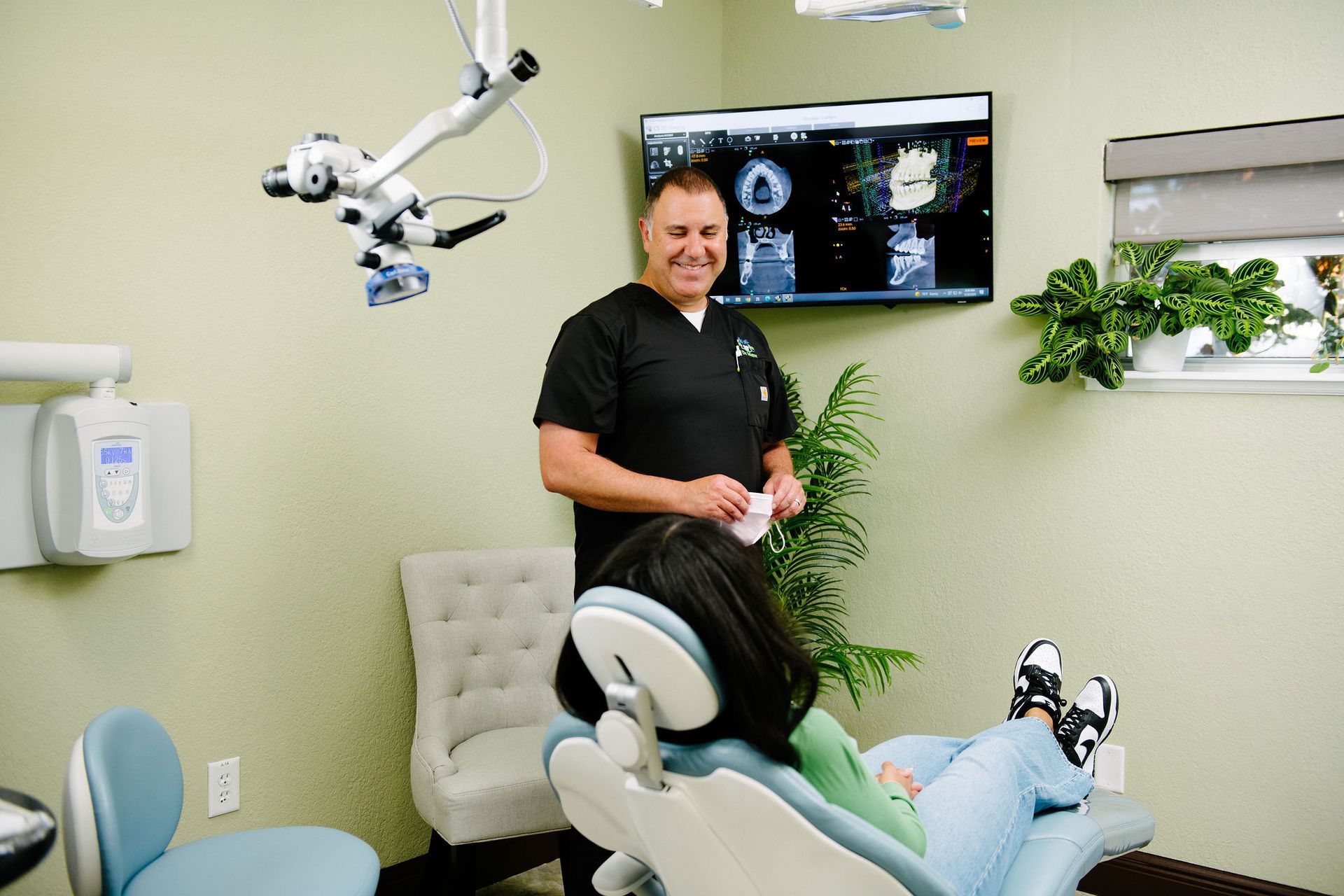 A dentist is standing next to a patient in a dental chair.