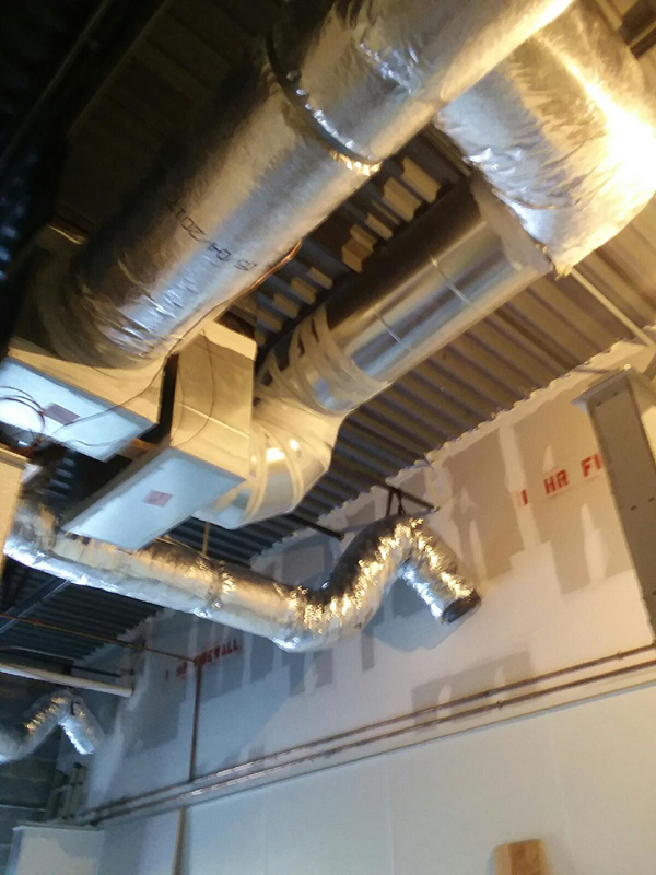 HVAC ductwork and equipment installed in a commercial space ceiling. Silver, white and gray components.