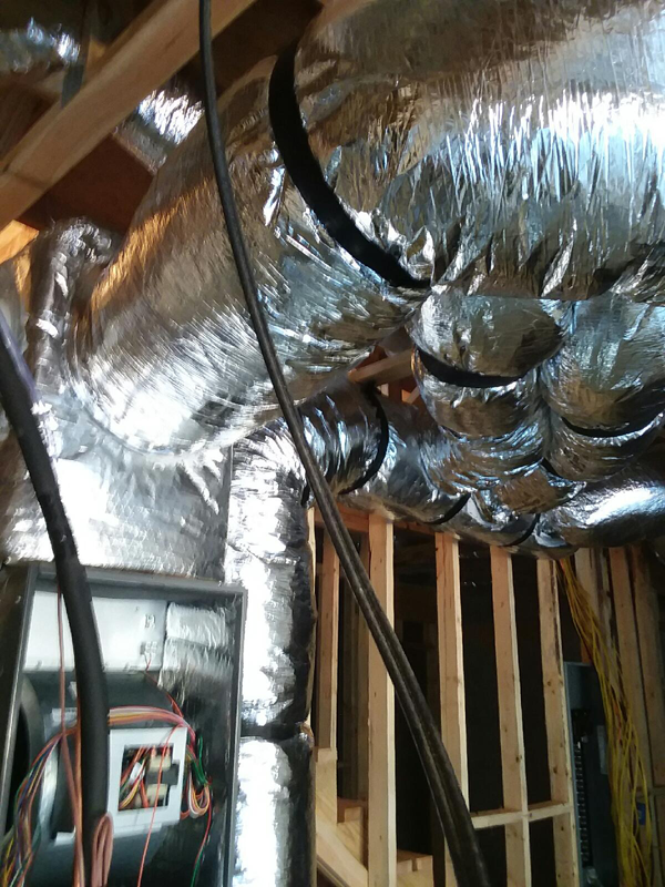 Insulated HVAC ductwork and electrical wiring in a construction setting.
