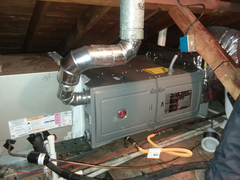 Furnace unit in an attic with ductwork, electrical connections, and gas line.