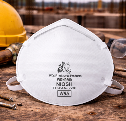 White NIOSH N95 respirator mask on a wooden table, with a yellow hard hat in the background