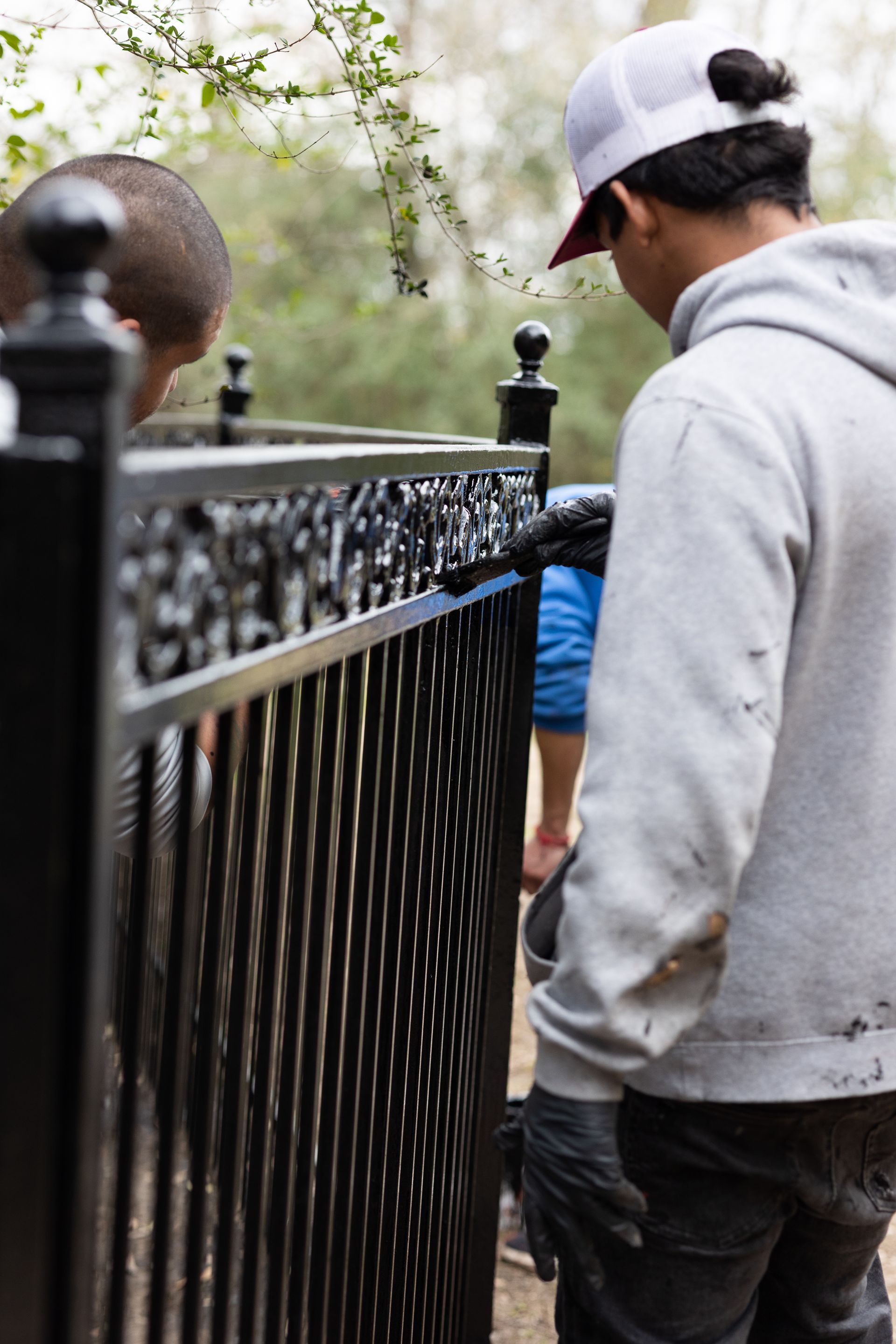 A man in a hat is standing next to a fence.