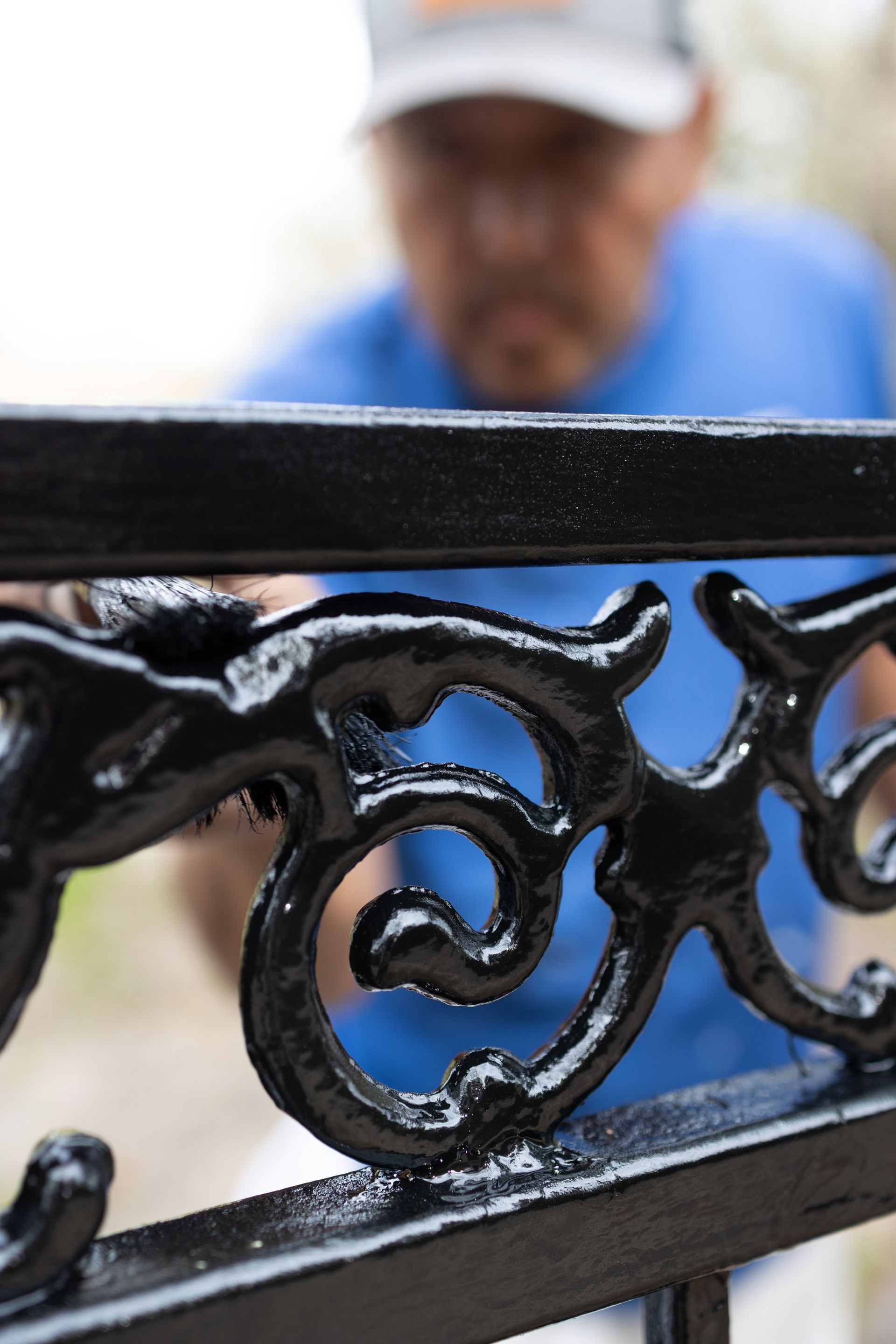 A man in a blue shirt is working on a black fence