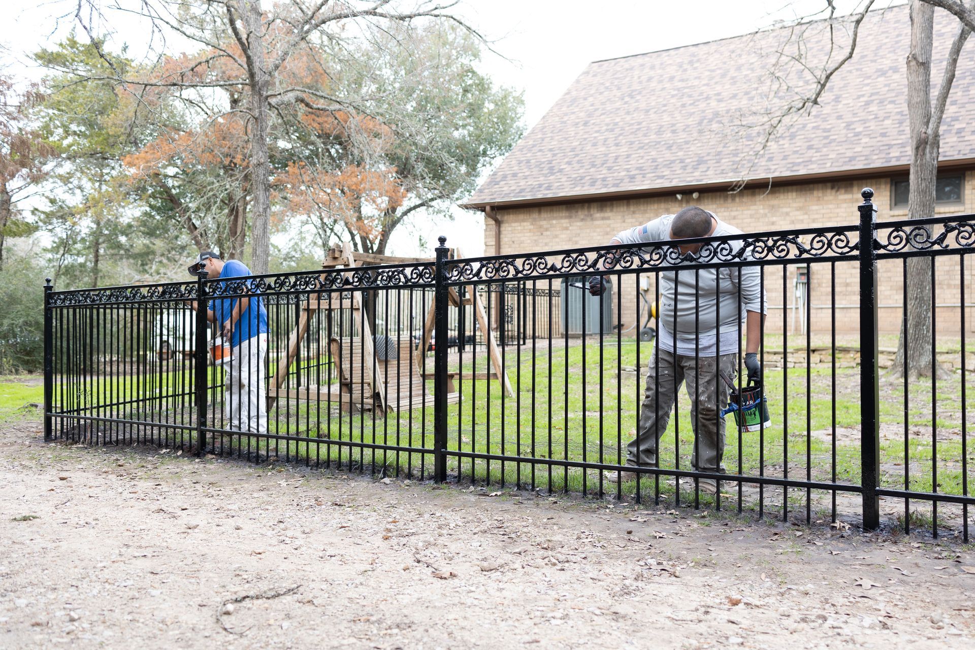 A man is standing behind a metal fence in front of a house.