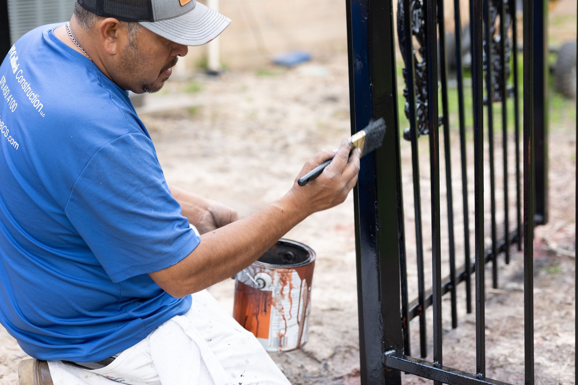 A man is painting a fence with a brush.