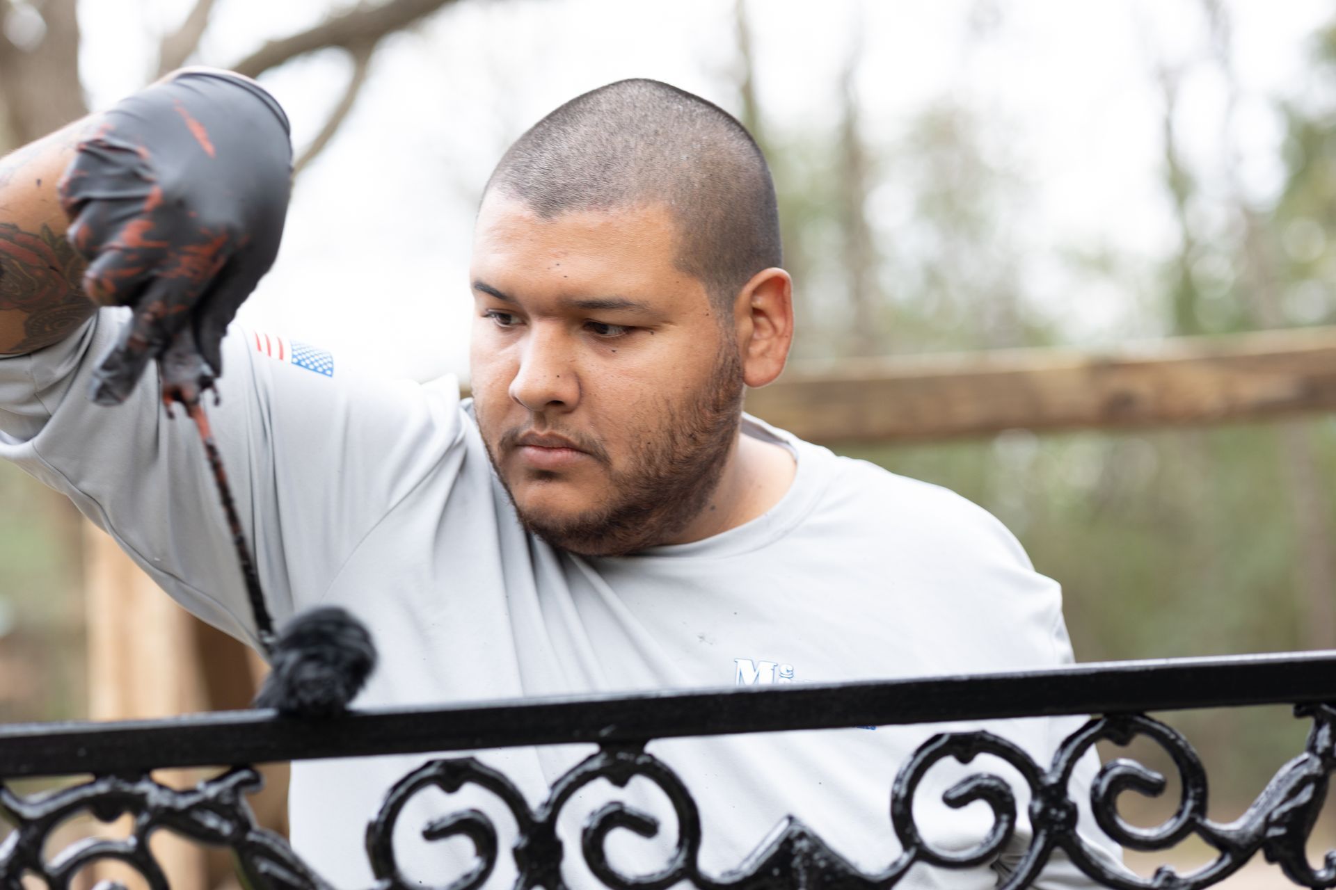 A man is working on a wrought iron fence.