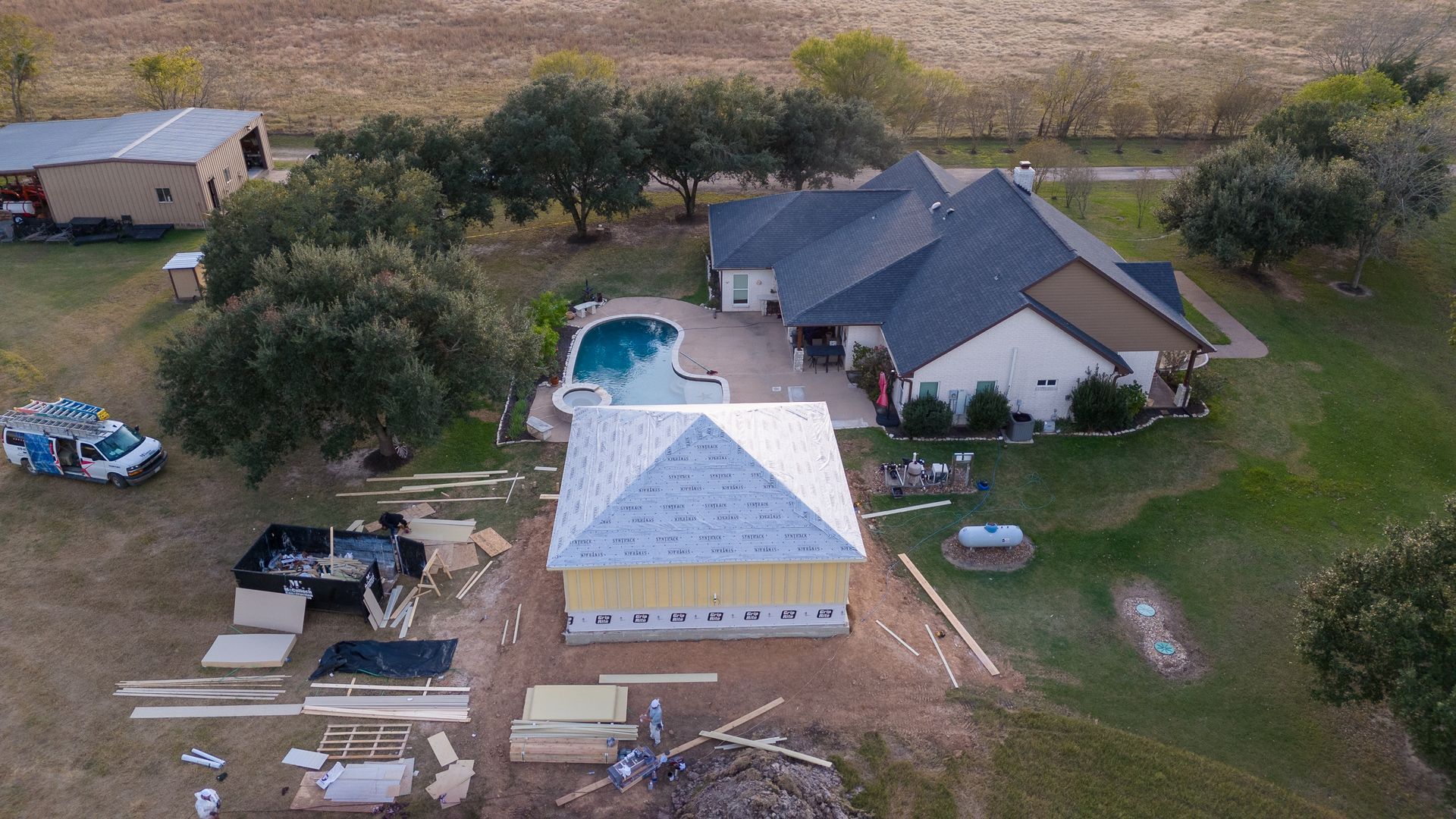 An aerial view of a house under construction with a pool in the backyard.