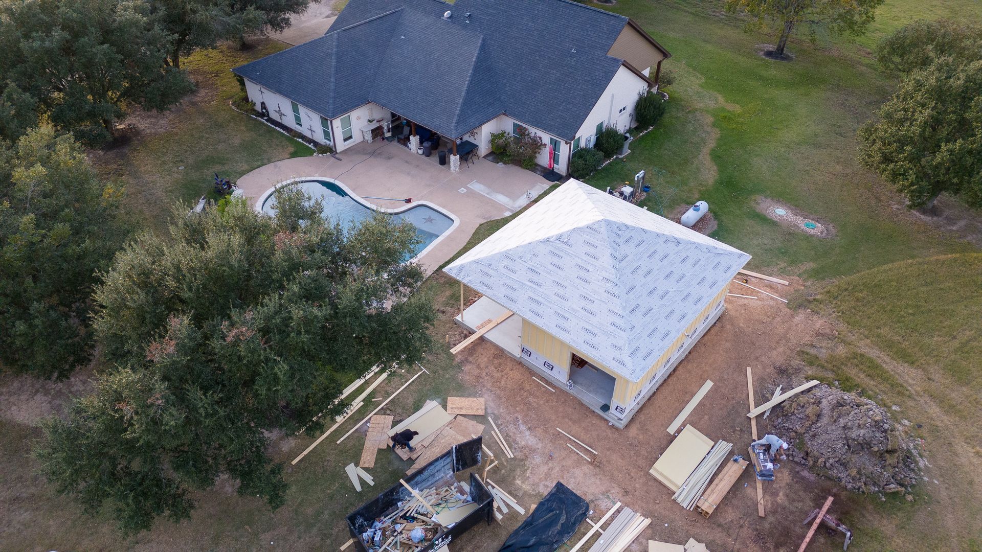 An aerial view of a house under construction with a pool in the backyard.