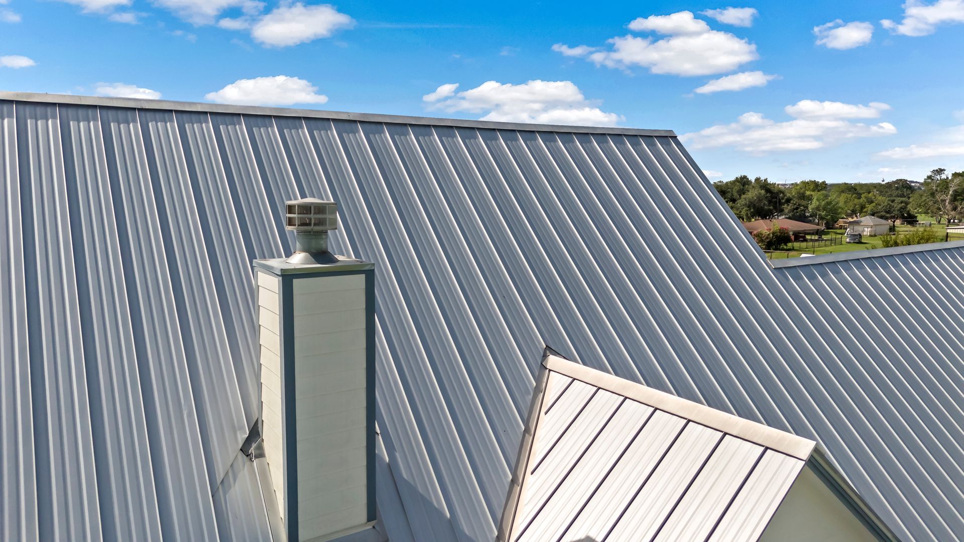 A roof with a chimney on it and a blue sky in the background.
