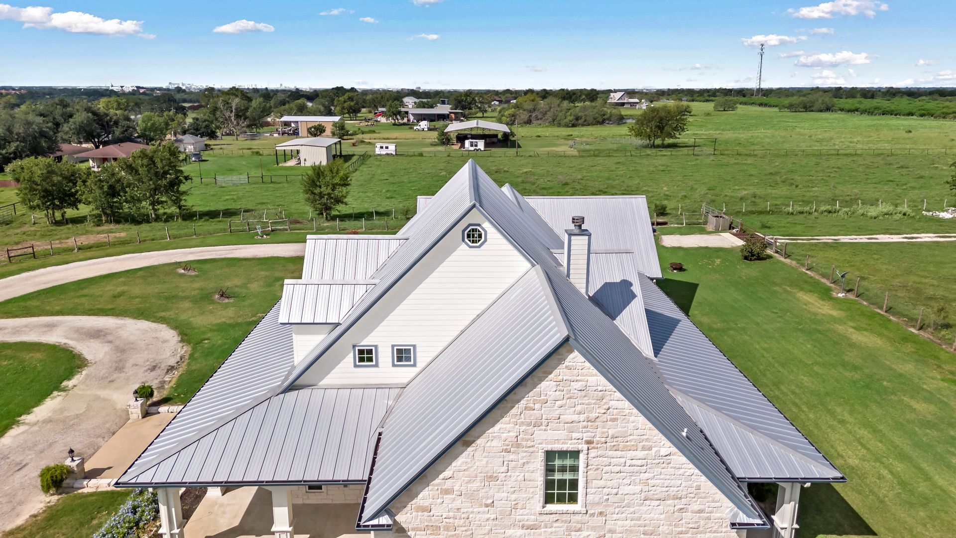An aerial view of a large house in the middle of a grassy field.