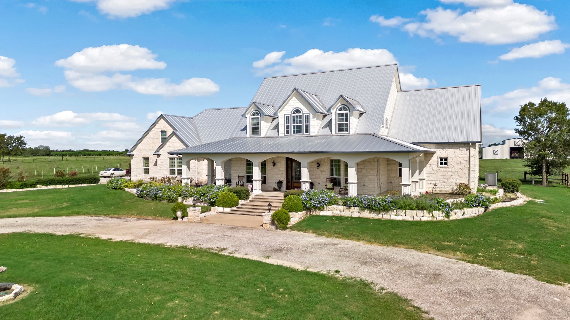 A large white house is sitting on top of a lush green field.