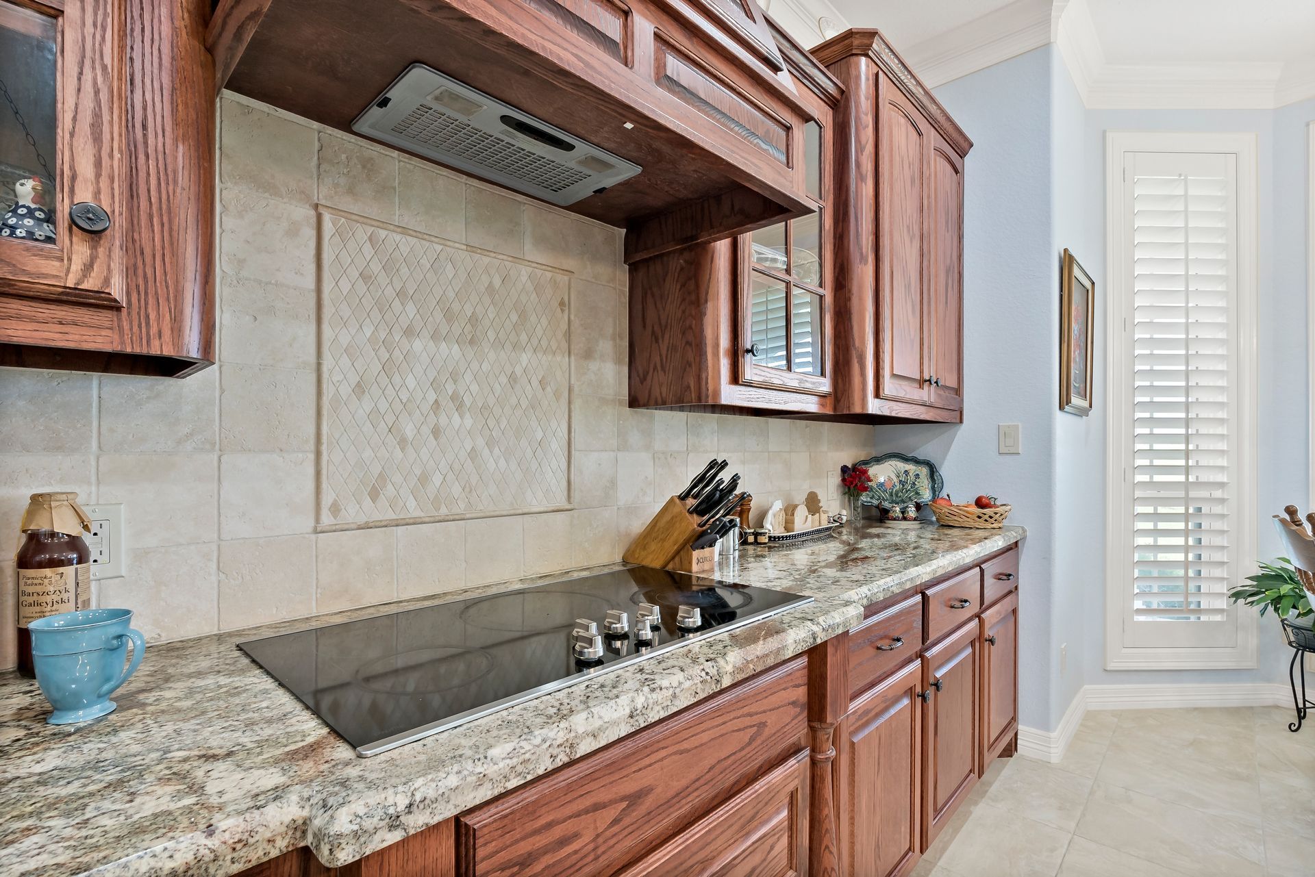 A kitchen with wooden cabinets , granite counter tops , and a stove top oven.