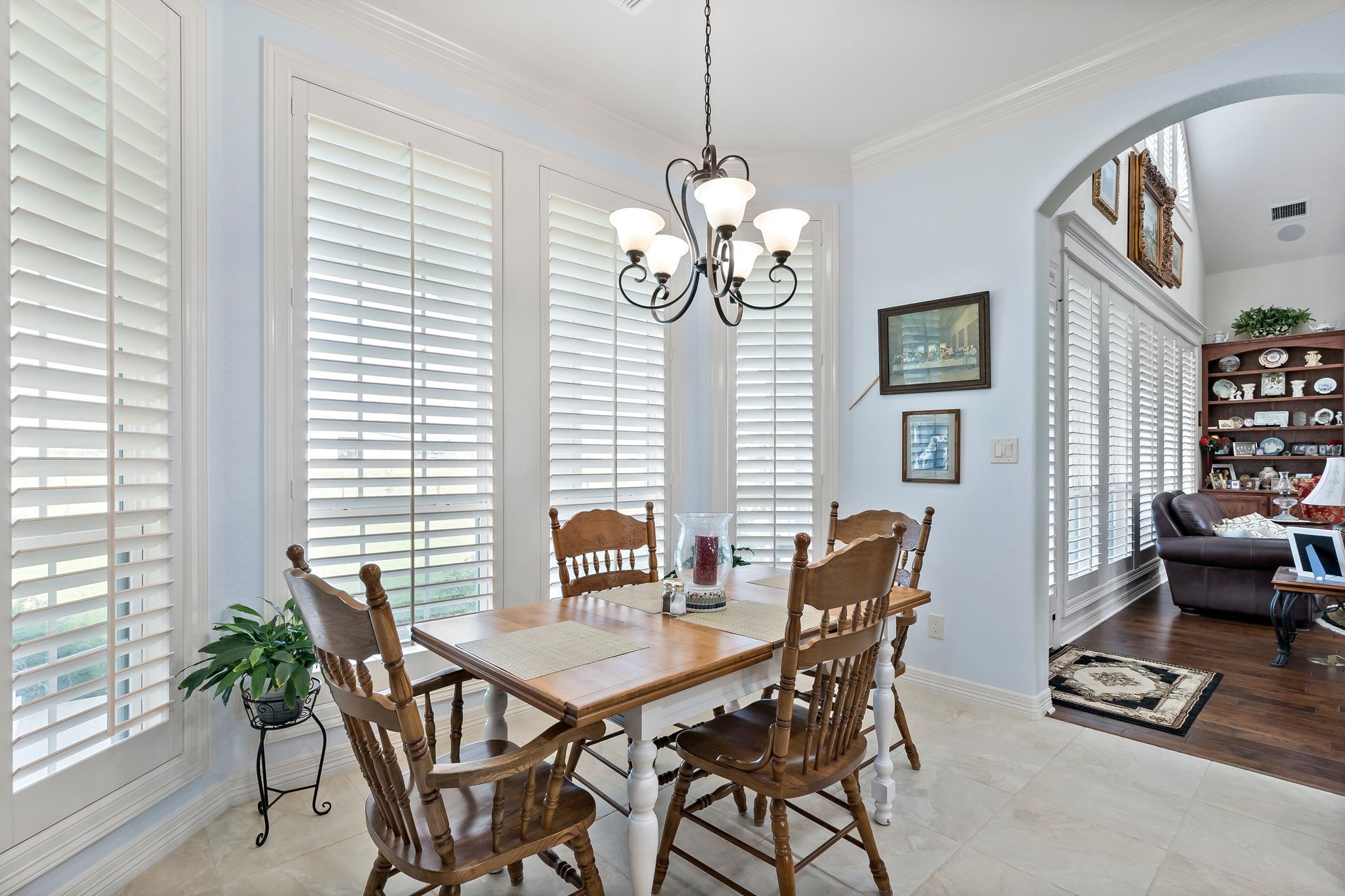 A dining room with a table and chairs and shutters on the windows.