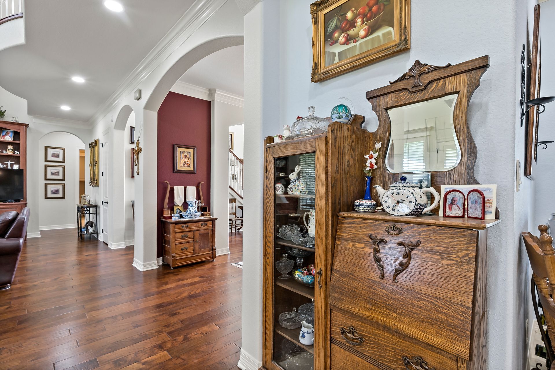A living room with hardwood floors and a wooden cabinet with a mirror on top of it.