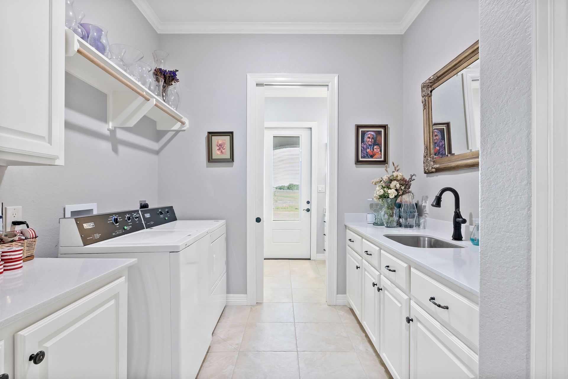 A laundry room with a washer and dryer , sink , and mirror.